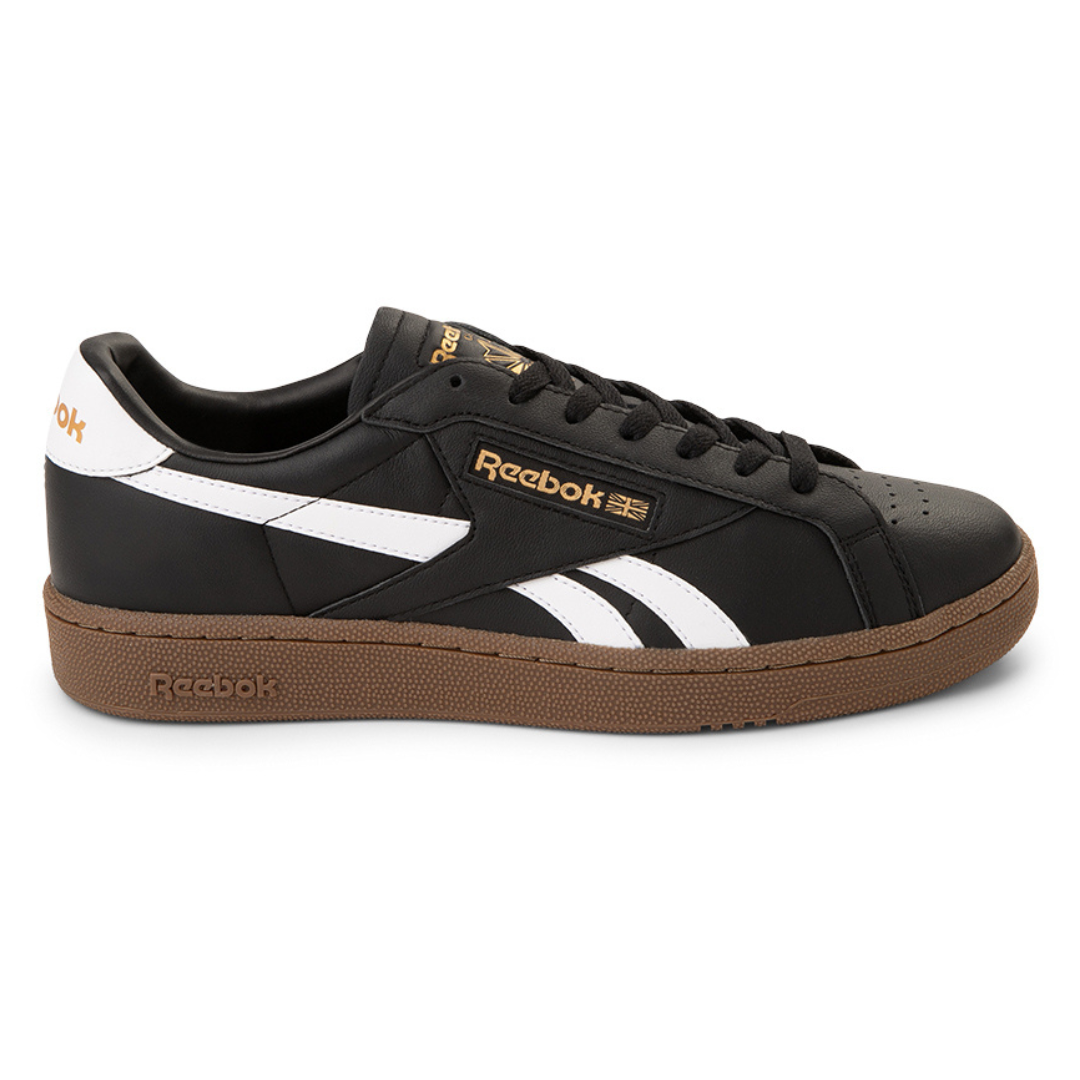 Reebok Club C Grounds UK Shoes feature a black leather upper with white accents, a brown rubber sole, and gold branding. The design includes the Reebok logo and a classic sporty look.
