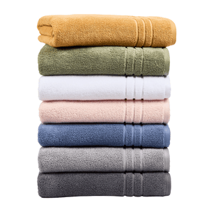 A stack of six neatly folded towels in various colors: mustard yellow, olive green, white, light pink, blue, and two shades of gray.