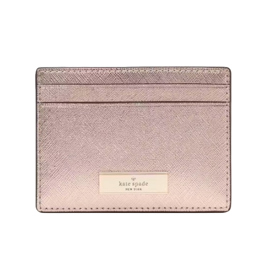 The Kate Spade Kenzie Metallic Card Holder is a sleek, shimmering pink accessory with two card slots and a gold logo plaque on the front.