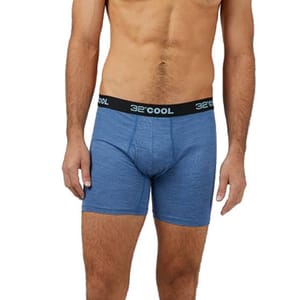 A man is wearing blue boxer briefs with a black waistband labeled \“32° COOL.\“