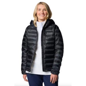 Columbia Down Hooded Jacket in black features a hood, quilted design for insulation, and Columbia logo on the chest. It's worn by a person with a white inner layer and navy pants.