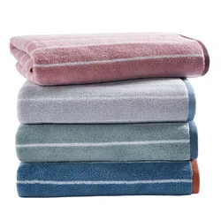 A stack of four towels in different colors: pink, gray, green, and blue, each with thin horizontal stripes near the edges.