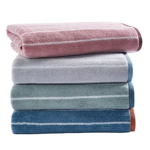 A stack of four towels in different colors: pink, gray, green, and blue, each with thin horizontal stripes near the edges.