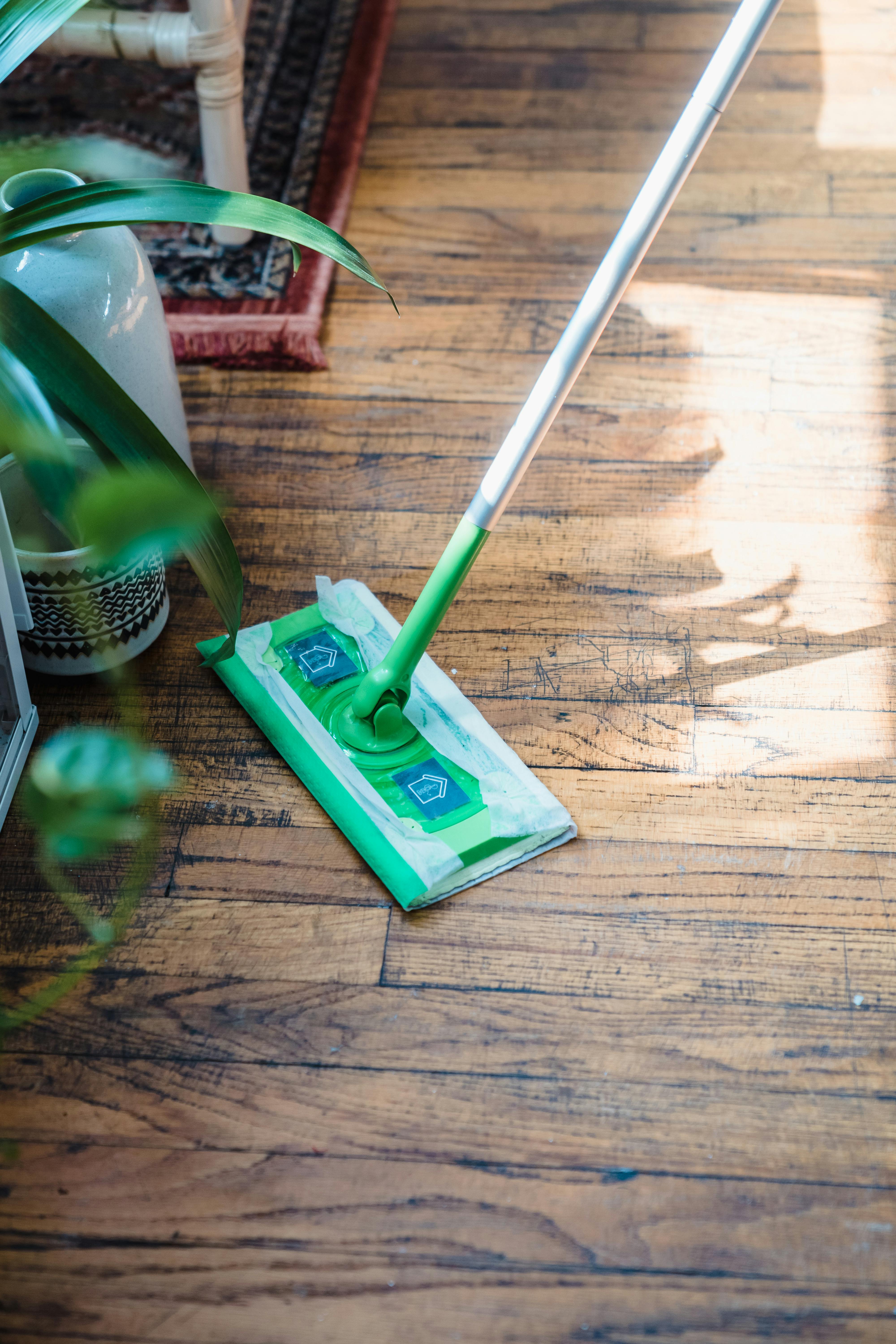 Flat mop with disposable cleaning pad on a hardwood floor.