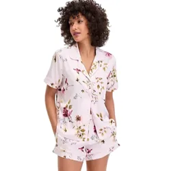 A woman is wearing a light pink, floral-patterned pajama set with a short-sleeve button-up top and matching shorts.
