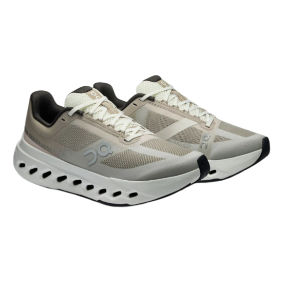Athletic shoes with a beige and black color scheme, featuring mesh panels, lace-up closure, and a distinctive sole with circular cutouts for ventilation.