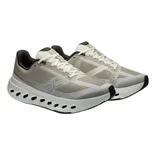 Athletic shoes with a beige and black color scheme, featuring mesh panels, lace-up closure, and a distinctive sole with circular cutouts for ventilation.