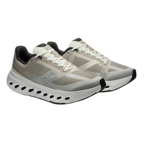 Athletic shoes with a beige and black color scheme, featuring mesh panels, lace-up closure, and a distinctive sole with circular cutouts for ventilation.