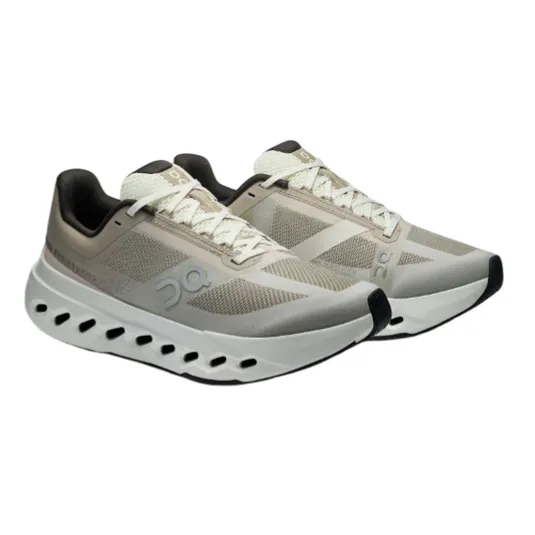 Athletic shoes with a beige and black color scheme, featuring mesh panels, lace-up closure, and a distinctive sole with circular cutouts for ventilation.