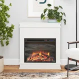 The Tereza 29.7\“W Electric Fireplace features a sleek, white mantle with a realistic, glowing log display. It includes a digital control panel and is surrounded by contemporary decor and greenery, fitting well in modern living spaces.