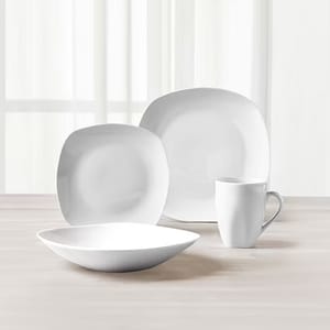 A set of white dinnerware including two plates of different sizes, a bowl, and a mug.