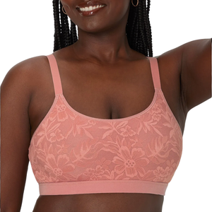 A woman wearing a pink lace bra with floral patterns is shown from the shoulders to the waist.