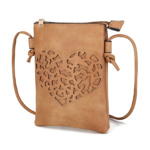 Tan faux-leather crossbody bag with a detailed laser-cut heart design on the front, a zipper closure, and adjustable strap with knotted ends.