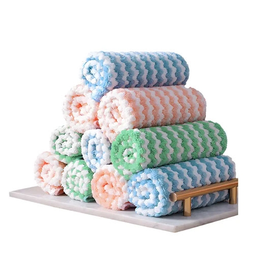 A stack of colorful rolled towels with a zigzag pattern in shades of blue, pink, and green, displayed on a wooden and marble holder.