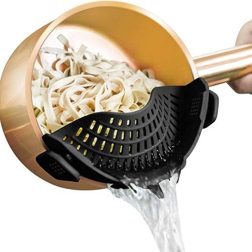 A black strainer clipped on to a copper-colored pot.