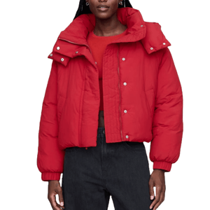 A red, cropped puffer jacket with a high collar, snap buttons, and elastic cuffs, worn over a red top and dark jeans.