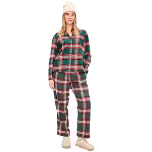 A person is wearing a green and red plaid pajama set, along with a beige knit hat and beige slippers.