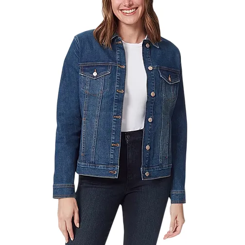 A woman is wearing a blue denim jacket over a white shirt, paired with dark jeans. The jacket features a button-up front and chest pockets.