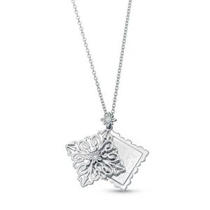 A silver necklace featuring a filigree snowflake pendant and a rectangular pendant with scalloped edges, both adorned with small gemstones.