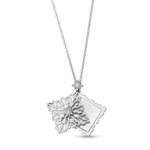 A silver necklace featuring a filigree snowflake pendant and a rectangular pendant with scalloped edges, both adorned with small gemstones.