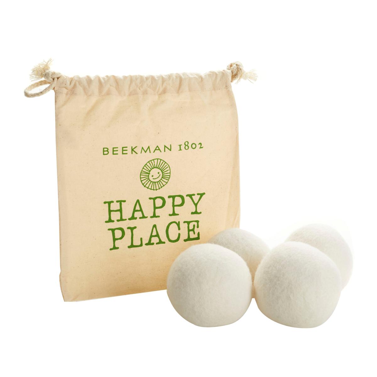 A drawstring bag labeled \“Beekman 1802 Happy Place\“ contains four white wool dryer balls.
