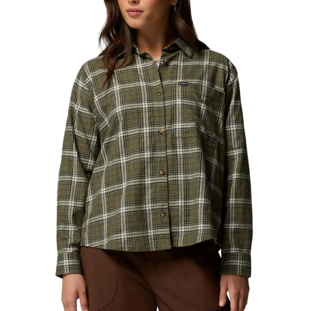 A woman is wearing a long-sleeve, olive green and white plaid button-up shirt paired with brown pants.
