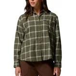 A woman is wearing a long-sleeve, olive green and white plaid button-up shirt paired with brown pants.