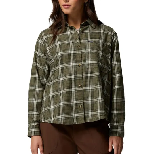 A woman is wearing a long-sleeve, olive green and white plaid button-up shirt paired with brown pants.