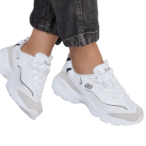 A person wearing white Skechers D'Lites sneakers with black detailing and light beige accents, paired with rolled-up dark jeans.