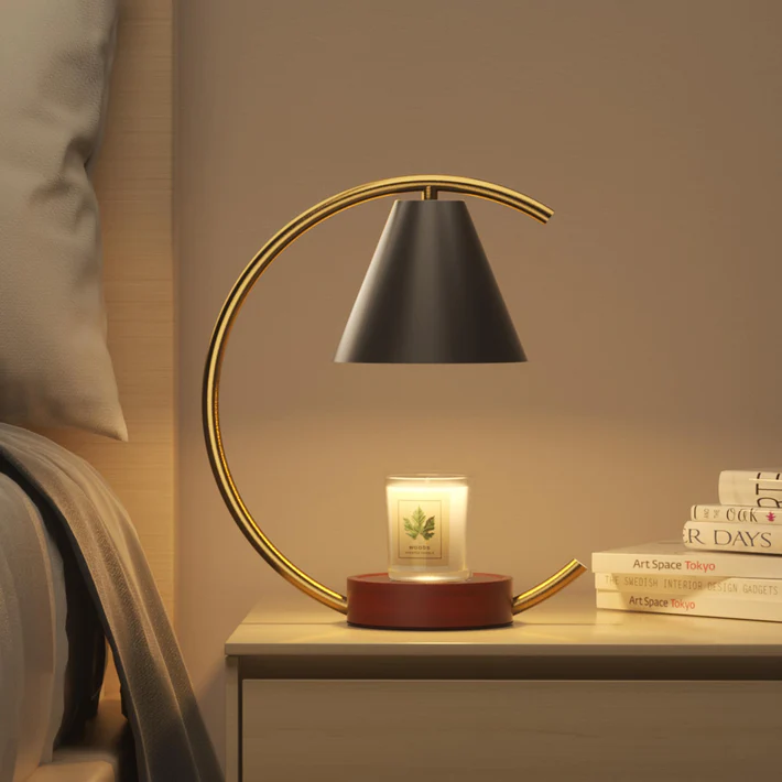 A modern arching table lamp with a black lampshade beside a scented candle on a nightstand.