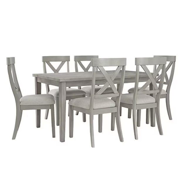 The 7-piece Signature Design by Ashley Dining Set features a rectangular gray table with a wood finish and six matching chairs with X-shaped backrests and upholstered seats.