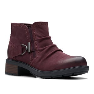 A maroon ankle boot with a ruched design, buckle detail on the side, and a low stacked heel.