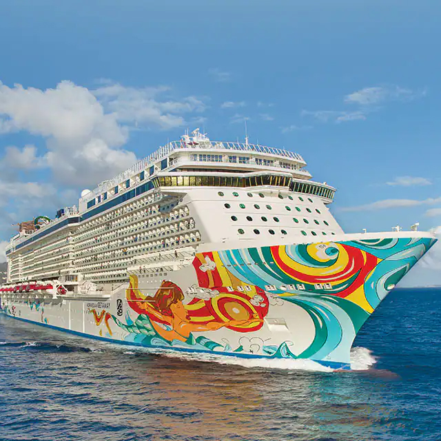 A brightly decorated cruise ship navigates the ocean under a partly cloudy sky, featuring vivid, colorful designs on its hull.