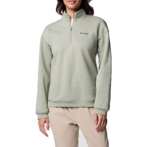 A woman wearing a Columbia mint green quarter-zip fleece pullover with a small logo on the left chest, paired with beige pants.