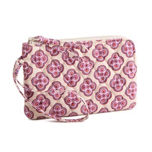 A quilted wristlet with a geometric floral pattern in pinks and purples on a beige background. It features a zipper closure and a matching strap.