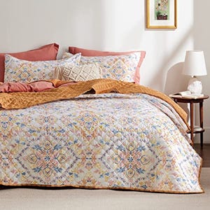 Quilt set featuring a patterned boho design with complementary pillow shams in a coordinated color palette.