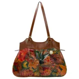 A floral-patterned handbag with brown leather handles and trim, featuring rich autumnal hues and a decorative pendant charm.