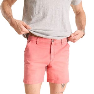 A person wearing coral pink shorts and a light gray T-shirt, showcasing casual summer attire.