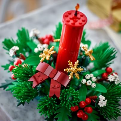 LEGO Christmas decoration featuring a red candle with festive greenery, red berries, white flowers, and a red bow.