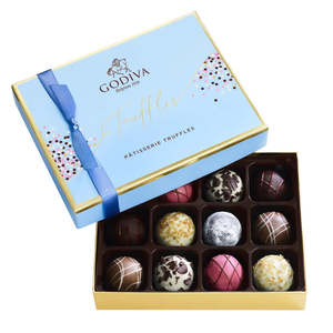A box of Godiva Patisserie Truffles is shown, featuring an assortment of finely decorated chocolate truffles in various flavors, packaged in a light blue and gold box with a blue ribbon.
