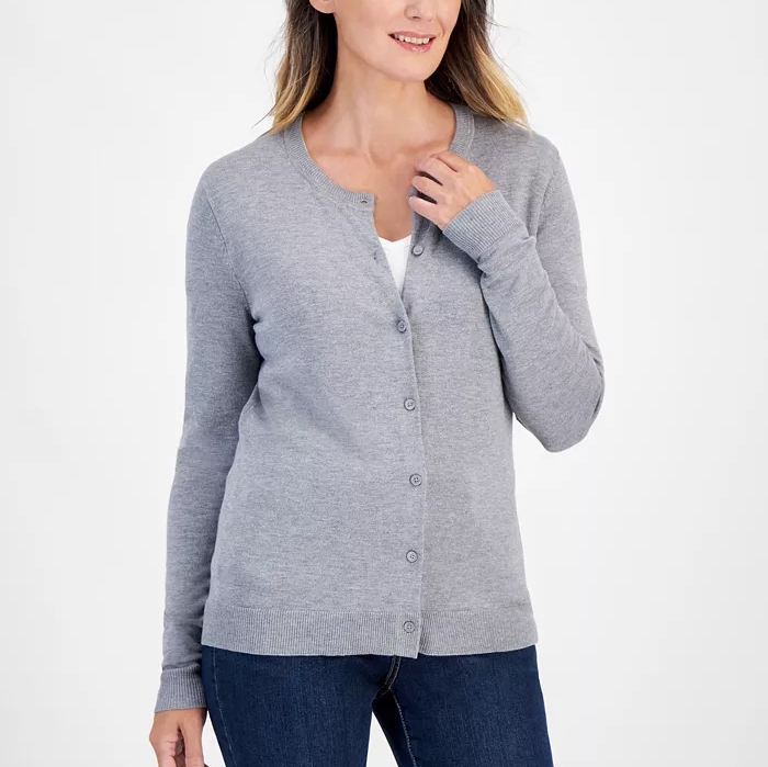 A woman is wearing a long-sleeve, light gray cardigan over a white top, paired with dark blue jeans.