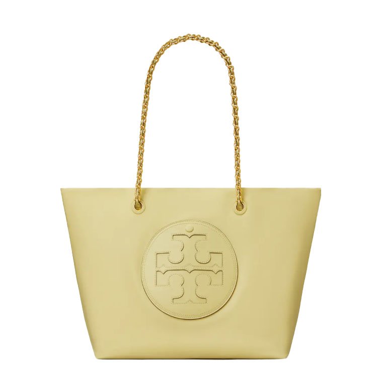 The Tory Burch Ella Chain Tote is a yellow tote bag featuring a large embossed logo on the front and two gold chain handles. It's a spacious and stylish accessory for carrying essentials.