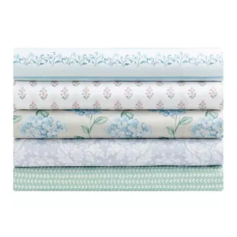 Stack of five folded fabrics with various floral and geometric patterns in blue, green, and white tones.