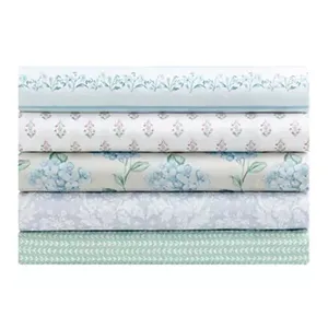 Stack of five folded fabrics with various floral and geometric patterns in blue, green, and white tones.
