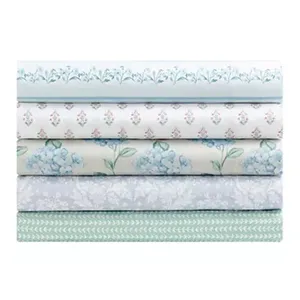Stack of five folded fabrics with various floral and geometric patterns in blue, green, and white tones.