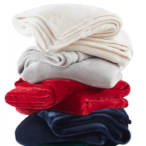 A stack of folded soft blankets in different colors: cream, gray, red, navy, and green.