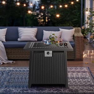 A stylish outdoor patio scene with a wicker-style fire pit table adorned with candles and a flower arrangement; string lights and a wicker sofa with cushions create a cozy ambiance.