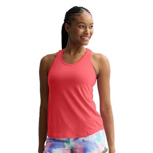 A woman is wearing a pink racerback workout tank with a scoop neckline, paired with colorful tie-dye shorts. The tank is sleeveless, offering a comfortable fit ideal for exercise.