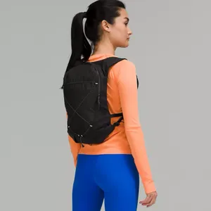 A person wears a black backpack, an orange long-sleeve top, and blue leggings.