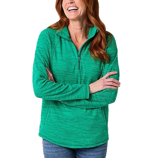 A woman wearing a green half-zip pullover sweater with full sleeves and light blue jeans, smiling with arms crossed.